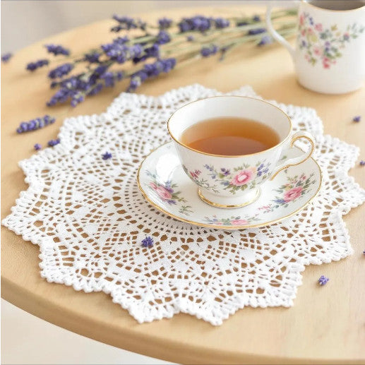 centrino bianco ad uncinetto su un tavolo con sopra una tazza di the
