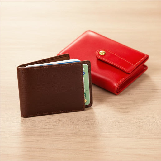 portafoglio marrone uomo e portafoglio rosso donna in pelle su un tavolo