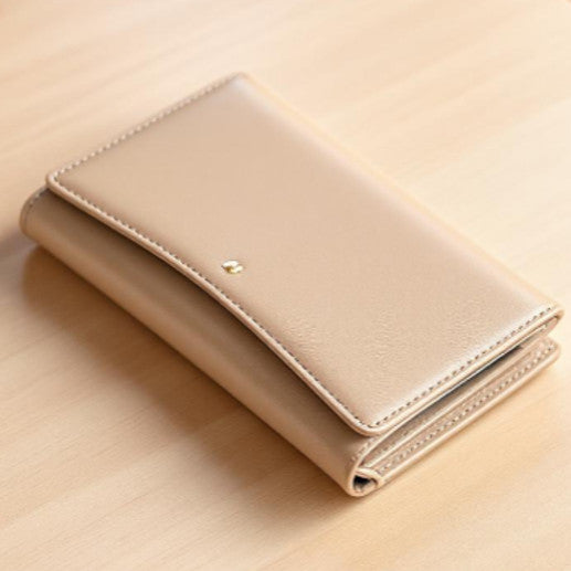 portafoglio donna beige in pelle su un tavolo 